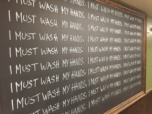 I MUST WASH MY HANDS written repeatedly on a chalk board